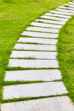 White granite walkway slabs patterned in green lawns at the gardenの写真素材