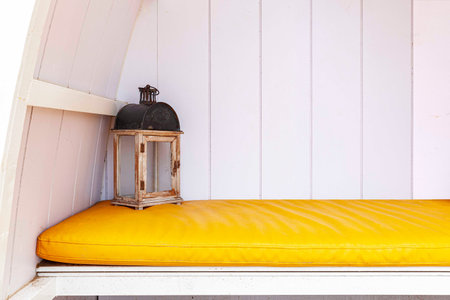 Clean white wooden sofas and bright yellow fabric cushions in the garden outside the house