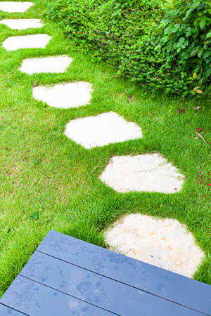 White granite walkway slabs patterned in green lawns at the gardenの写真素材