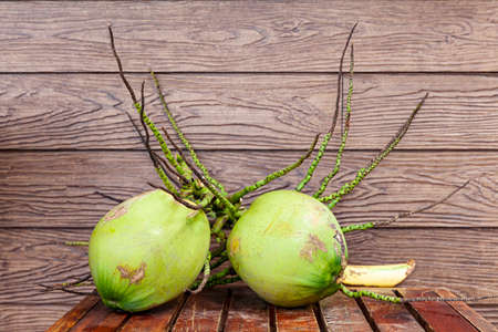 Fresh green coconuts are placed on a wooden table at a fruit shopの写真素材