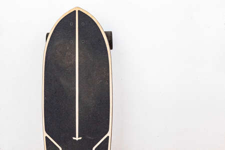 A black skateboard is placed on a white cement wall.の写真素材