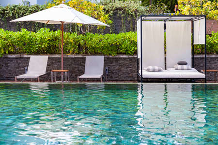 Wide swimming pool and brown wood floor inside the villaの写真素材