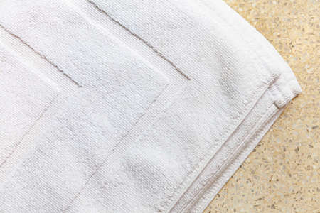 Clean white towels folded on a brown wood table.の写真素材