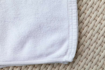Clean white towels folded on a brown wood table.の写真素材