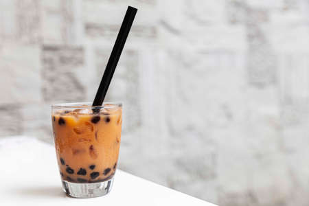 Thai tea with milk in a glass jar placed on a wooden tableの写真素材