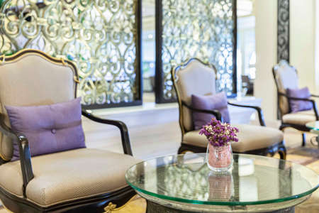 Purple plastic flowers in a glass vase decorate the living room of a luxury homeの写真素材