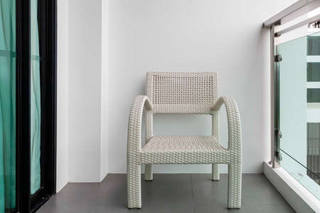 Empty white rattan chair on balcony on high rise buildingの写真素材