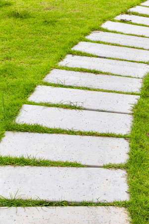 White granite walkway slabs patterned in green lawns at the gardenの写真素材