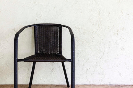 Empty black plastic rattan chair on the balcony of the house