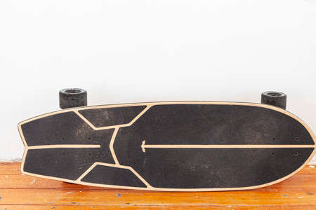 A black skateboard is placed on a white cement wall.の写真素材