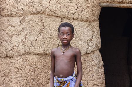 Gaoua,Burkina Faso - August 12,2009: Lobi ethnic girl in the doorway of his house, the children take care of their houses while the women cook.のeditorial素材