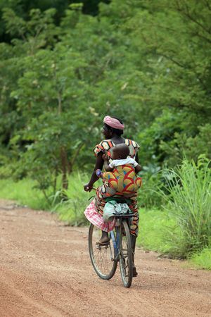 Tiebele, Burkina Faso - August 11, 2009: African Woman carrying her baby by bicycle, the bicycle is the popular Means of transport,のeditorial素材