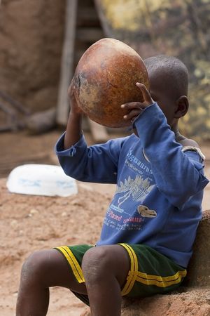 Gaoua, Burkina Faso - August 12.2009: Child of the Lobi ethnic eating, the lobi made from clay utensils for cookingのeditorial素材