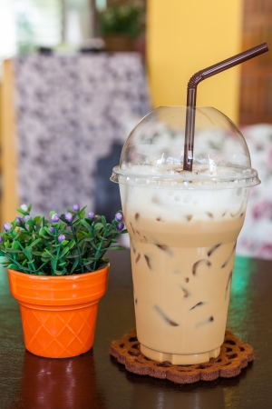 take-home cup of ice coffee on wooden table の写真素材