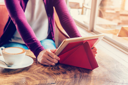 woman using tablet computer in coffee shop with vintage tone.