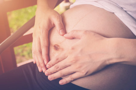 Pregnant Woman holding hand heart shape for baby in her tummyの写真素材