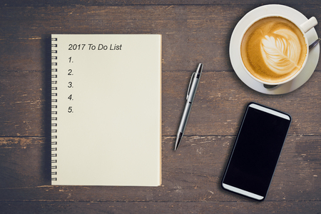 Business concept - Top view notebook writing 2017 To Do List, pen, coffee cup, and phone on wood table.の写真素材