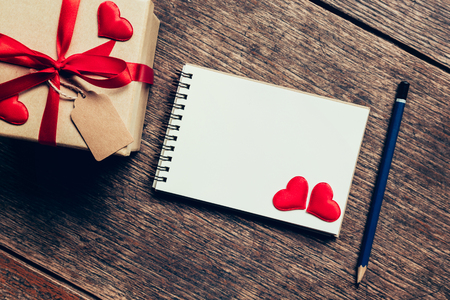 Top view (above) gift box and red ribbon and red heart with notebook for valentine on table wooden. Valentine background.の写真素材
