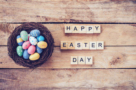Colorful easter egg in the nest and wood text for Happy Easter Day on wood background with spaceの写真素材