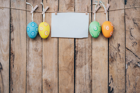 easter egg and blank paper for label hanging on wood background with space.の写真素材