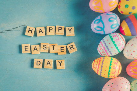 Colorful easter egg and wood text Happy Easter Day on blue pastel color wood background with space.の写真素材