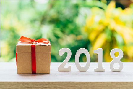 New Year concept for 2018 : Wood numbers 2018 on wood table top and gift box with green light bokeh...