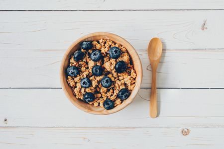 Homemade granola and fresh berries on wood table with space.の写真素材