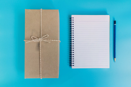 top view brown gift box and notebook paper on blue pastel color background.の写真素材