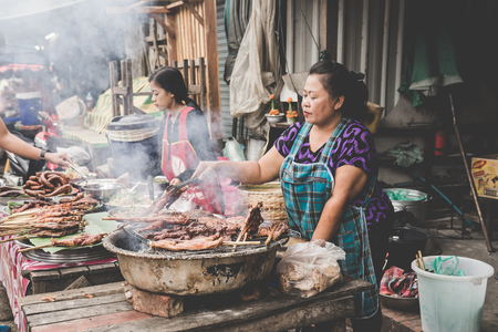 LUANG PRABANG, LAOS - NOVEMBER 17: A typical scene of a local hill tribe woman cooking on a barbecue at a roadside stall in Luang Prabang, Laos on the 13th NOVEMBER, 2017.のeditorial素材