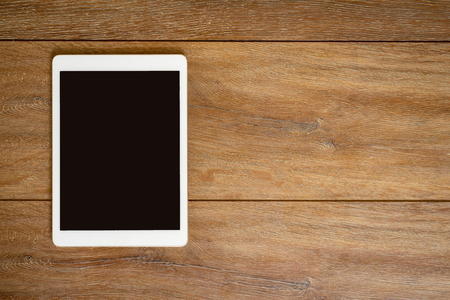 Blank Tablet computer on wood table background with space for text.の写真素材
