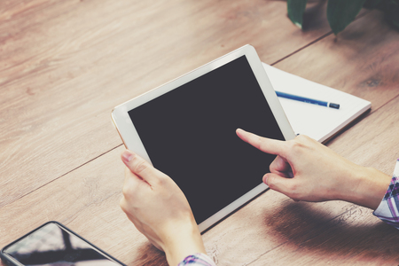 Hand woman using tablet computer on wooden table with Vintage toned.の写真素材