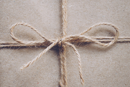 String or twine tied in a bow on paper textureの写真素材