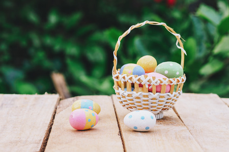 Colorful easter eggs in basket on wooden table win copy space.の写真素材