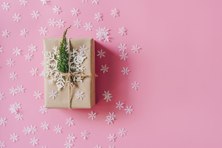 Brown gift box on the pink background with christmas decoration. Minimal styled holiday card with copy space.の写真素材