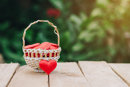 Red heart in basket on wooden table for valentine day and love concept with copy space.の写真素材