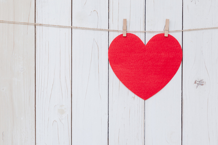 Red heart hanging on white wood  background with copy space.の写真素材