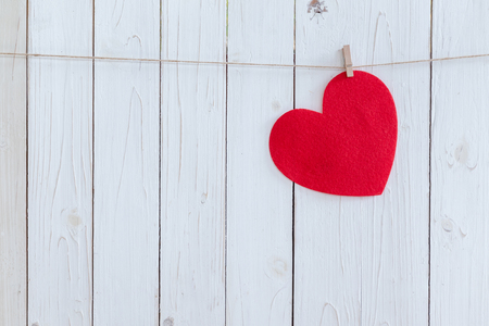 Red heart hanging on white wood  background with copy space.の写真素材