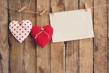 Heart and empty paper hanging on wood background with copy space.の写真素材