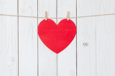 Red heart hanging on white wood  background with copy space.の写真素材