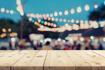 Empty wooden table and blurred background at night market festival people walking on road with copy space, display montage for product.の写真素材