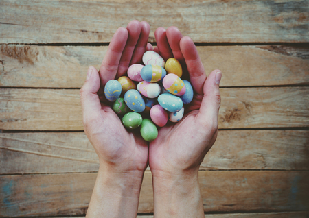 Hand woman holding colorful easter eggs on wood table background.の写真素材