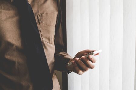 Businessman holding phone at window. Creative Business Startup Idea.の写真素材