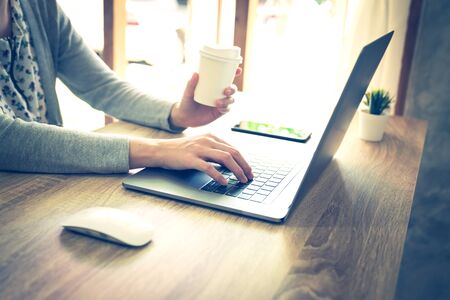 asian woman using laptop computer do online activity on wood table at home office.の写真素材