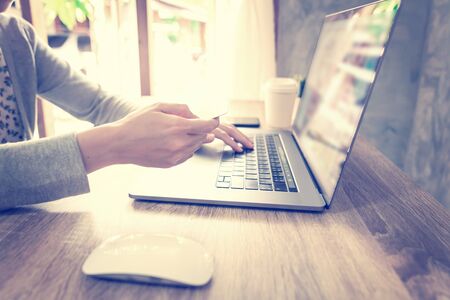 asian woman using laptop computer do online activity pay credit card on wood table at home office.の写真素材
