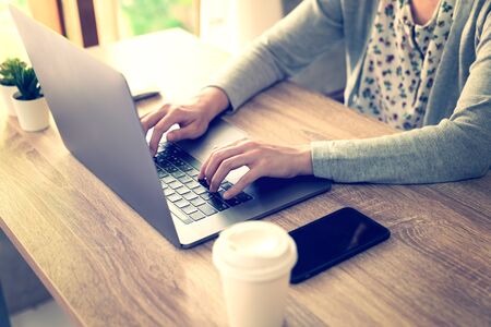 asian woman using laptop computer do online activity on wood table at home office.の写真素材