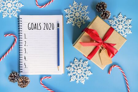 2020 New year concept. Goals 2020 list in notepad, gift box and christmas decoration on blue pastel color with copy spaceの写真素材