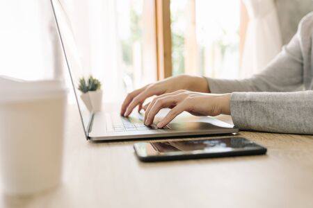 Business woman hand typing laptop computer on wooden tableの写真素材