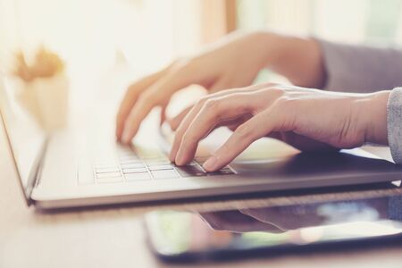 Business woman hand typing laptop computer on wooden tableの写真素材