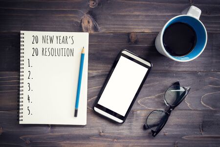 New Year goals, resolution or action plan 2020 concep. Office wood table with blank notepad, pencil, glasses, phone and cup of coffee.の写真素材