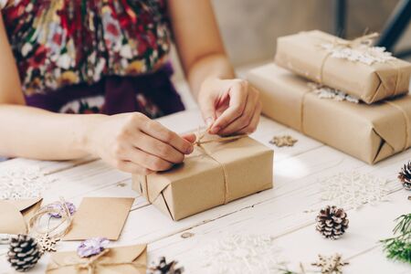 Close up of hands holding wrapping gift box on wooden table with xmas decoration.の写真素材
